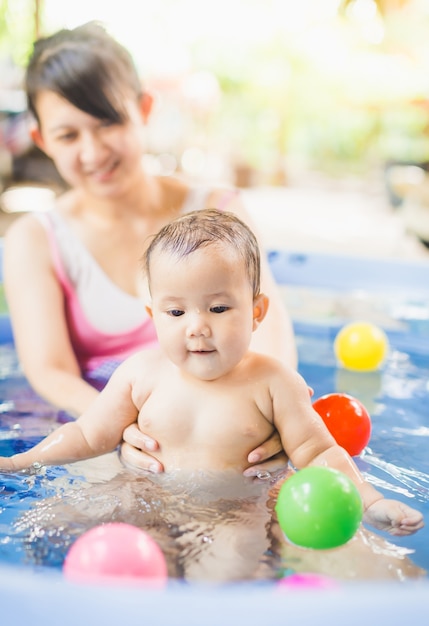 Photo 6 mois bébé jouant au ballon dans une petite piscine avec la mère