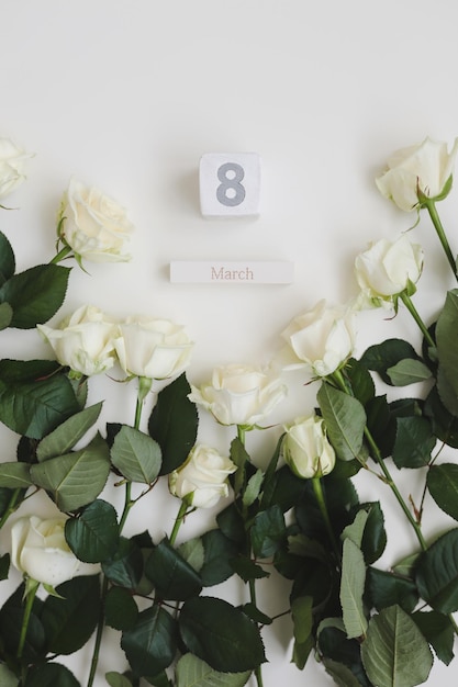 8 mars fond de la journée de la femme avec des roses blanches et place pour le texte sur la vue de dessus de fond blanc