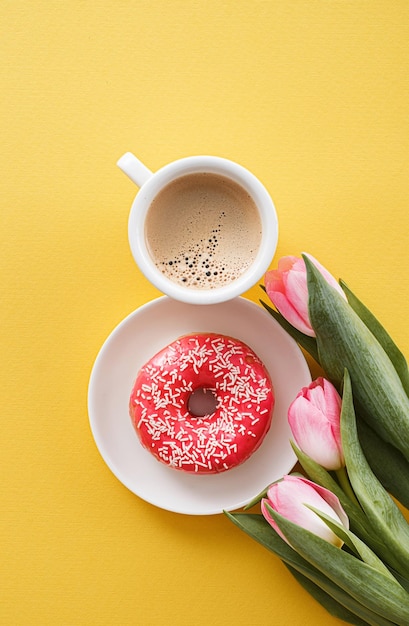 8 mars Journée internationale de la femme numéro huit composée d'une tasse de café et d'un beignet avec garniture rose à côté d'un espace de tulipes roses pour le texte