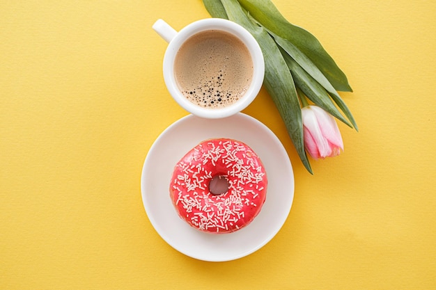 8 mars Journée internationale de la femme numéro huit composée d'une tasse de café et d'un beignet avec garniture rose à côté d'un espace de tulipes roses pour le texte