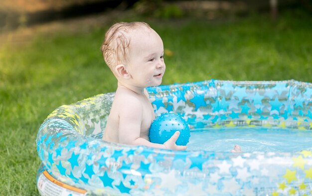 9 mois baby boy playing with ball in pool at garden