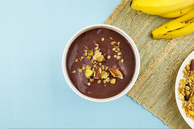 AÃƒÂ§ai brésilien dans un bol blanc avec banane, granola et châtaignes.