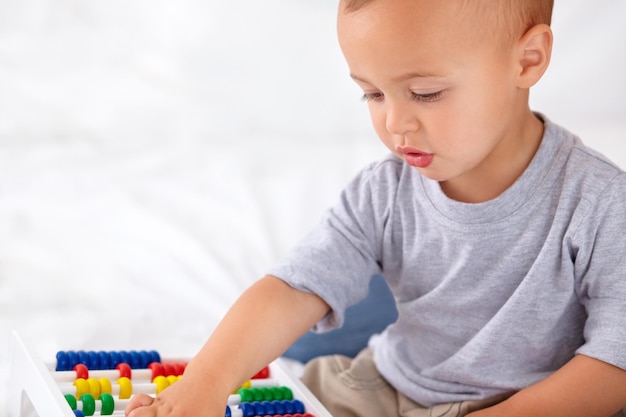 Abacus maths et garçon bébé apprenant à jouer et à enseigner pour le développement de l'enfant sur le lit Jeunesse préscolaire et gros plan de bébé ou tout-petit avec comptage pour le jouet dans la chambre à coucher ou la pépinière à la maison