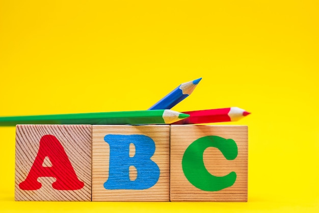Photo abc les premières lettres de l'alphabet anglais sur des cubes de jouets en bois sur fond jaune à côté de la col...