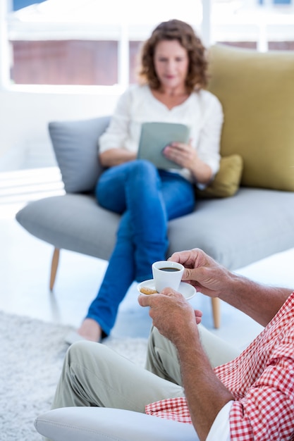 Abdomen d'homme tenant une tasse de café à la maison avec une femme