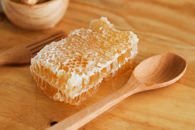 abeille avec nid d&#39;abeilles et louche sur la table en bois