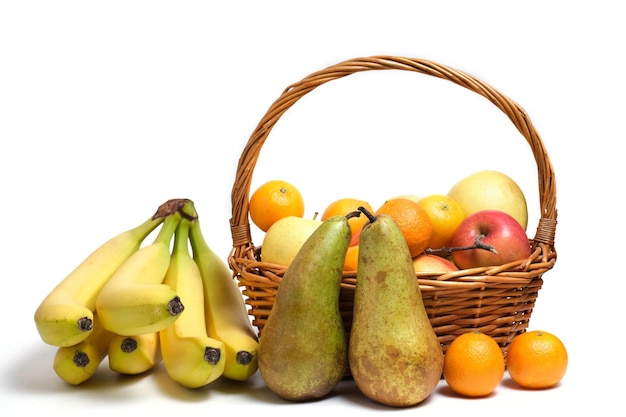 Abondance de fruits fond blanc dans le panier en osier, pommes, poires, agrumes et bananes.