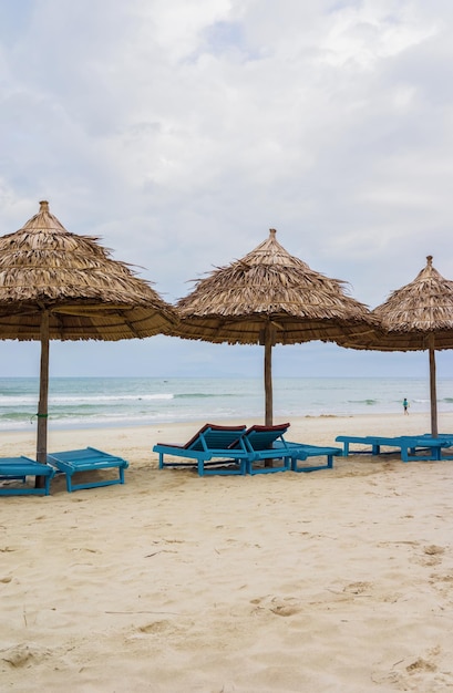 Abri de feuilles de palmier et transats dans la China Beach à Da Nang, Vietnam. Elle est aussi appelée plage de Non Nuoc. Mer de Chine méridionale en arrière-plan.