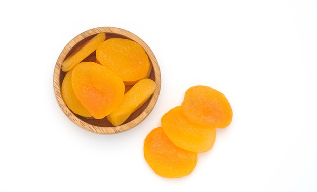 Abricot sec dans un bol en bois isolé sur fond blanc vue de dessus de fruits sains