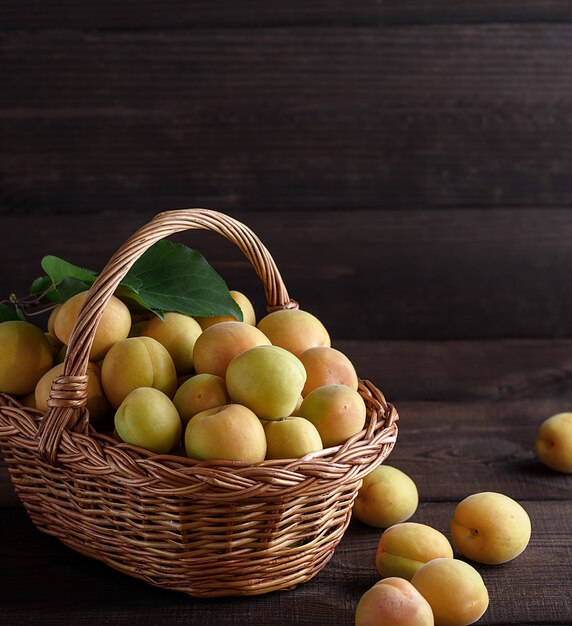 Abricots dans un panier en osier brun sur une table en bois