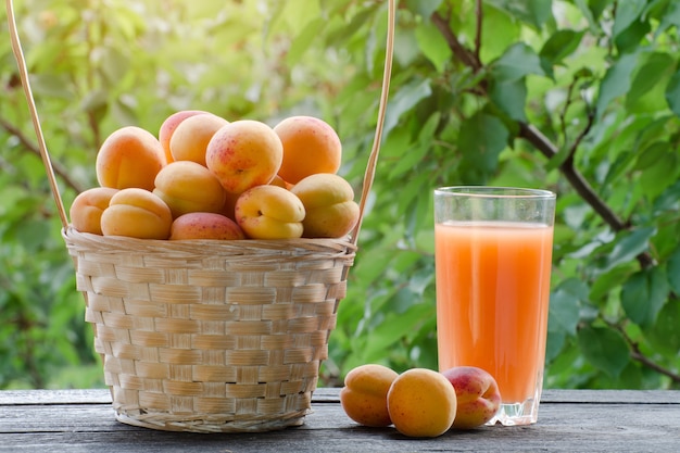 Abricots dans un panier en osier et un verre de jus