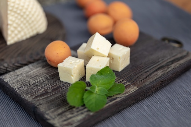 Abricots et feuilles de menthe faits maison de fromage cottage sur une planche de cuisine vintage