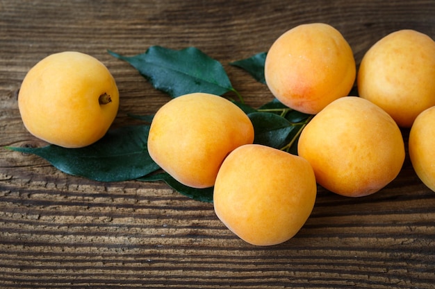 Abricots avec des feuilles sur la vieille table en bois