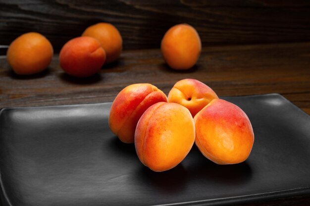 Abricots sur fond sombre Des abricots rouges juteux frais sont empilés sur une plaque d'argile sombre