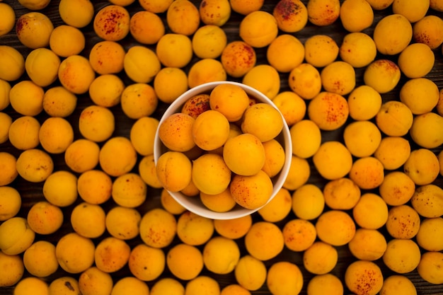 Abricots frais dans une assiette sur un fond en bois