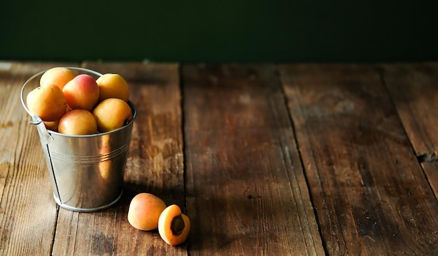 Abricots frais dans un seau en métal Abricots mûrs frais sur une table en bois