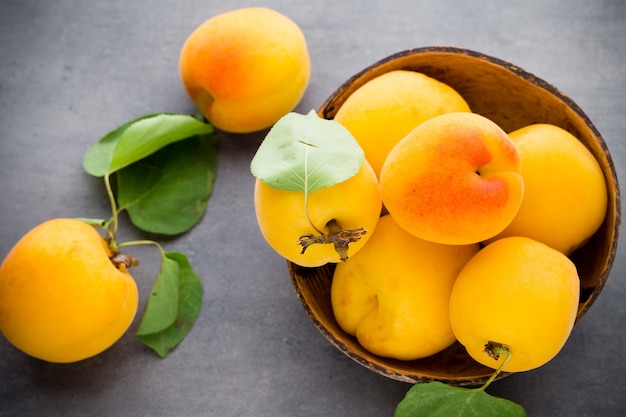 Abricots frais avec des feuilles sur la vieille table en bois.