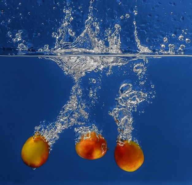 Abricots frais tombant dans l'eau sur fond sombre