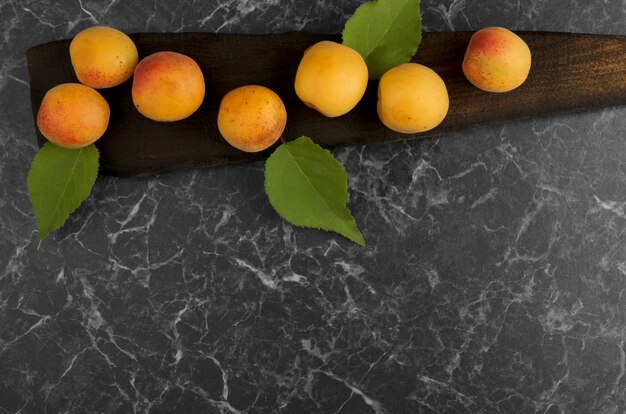 Photo abricots mûrs allongés sur un tableau sombre sur une surface sombre