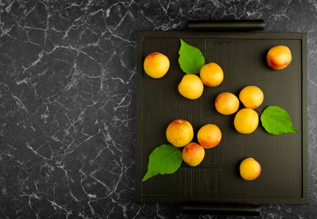 Abricots mûrs se trouvant sur un plateau noir