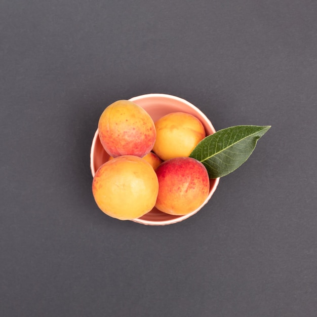 Abricots orange dans un bol sur un fond sombre Concept alimentaire minimal Mise à plat