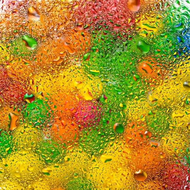 Photo abstrait coloré avec des gouttes d'eau sur la surface en verre.