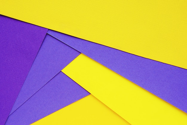 Abstrait géométrique feuilles de papier jaune et violet dans un ordre chaotique.