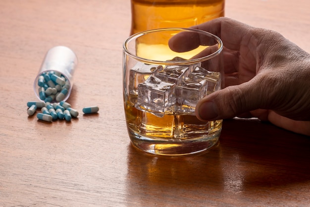 Photo l'abus d'alcool avec un verre de whisky avec de la glace et des pilules