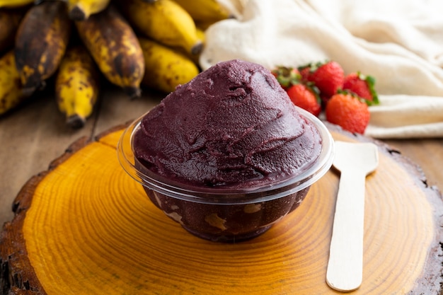 Acai, bol de crème glacée aux baies d'açai congelé brésilien avec des fraises et des bananes. avec des fruits sur une table en bois. Vue de face du menu d'été