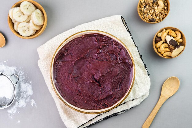 Acai brésilien dans un bol blanc granola de banane supplémentaire et noix dans de petits bols en bambou Noix de cajou et Para Vue de dessus Fond gris Mise au point sélective