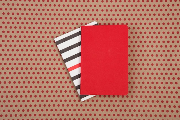 Accessoires de bureau bloc-notes rouges et rayés sur fond de papier kraft à pois rouges