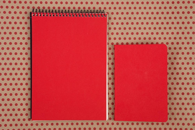 Accessoires de bureau deux blocs-notes rouges sur fond de papier kraft à pois rouges