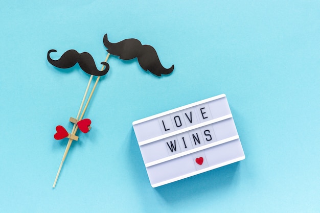 Accessoires de couple papier moustache et boîte à lumière avec texte Amour gagne sur fond bleu