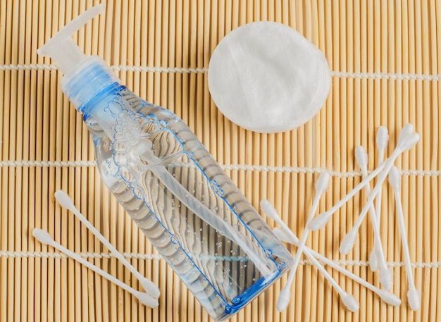 Accessoires démaquillants pour femmes. Gel en bouteille transparente, cotons-tiges, cotons-tiges sur tapis de bambou