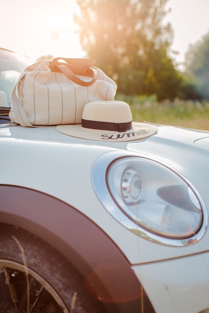 Les accessoires d'été se trouvent sur le capot de la voiture au soleil couchant.