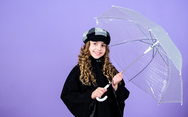 Les accessoires imperméables rendent les jours de pluie amusants Saison d'automne Profitez du concept de pluie Tendance de la mode pour enfants Aimez les jours de pluie Enfant fille heureuse tenir un parapluie transparent Profitez du temps pluvieux avec des vêtements appropriés