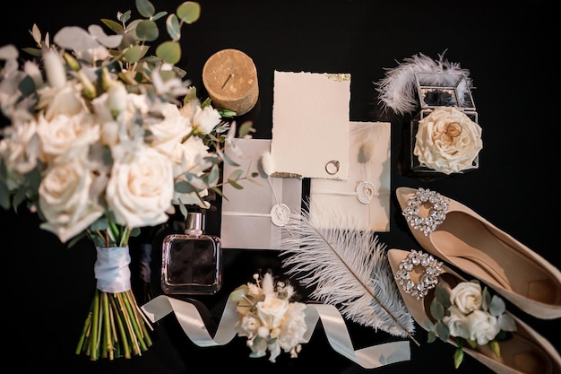 Des accessoires de mariée tels que des chaussures, des bagues de bouquet et des parfums sont posés sur une table