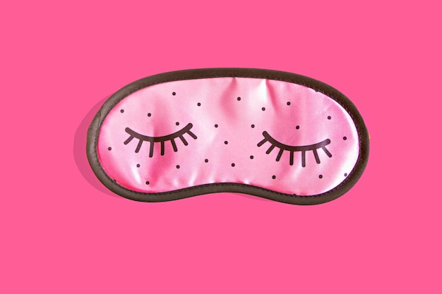 Accessoires de masque de sommeil rose pour les filles et les jeunes femmes aux yeux fermés sur fond rose Vue de dessus à plat Concept de protection des yeux pour de bons rêves et dormir