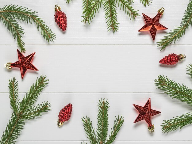 Accessoires de Noël rouge vif et branches d'épinette sur une surface en bois blanche