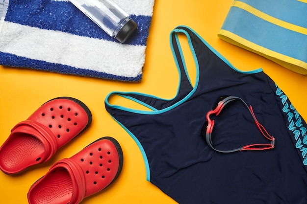 Accessoires de piscine d'été à plat sur fond jaune vêtements de plage colorés