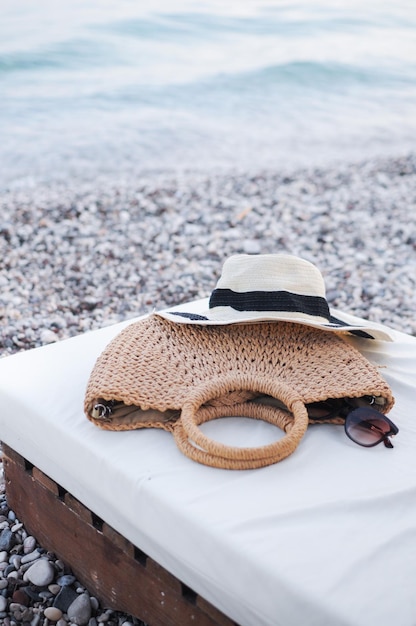 Accessoires de plage plat chapeau de paille sac d'été et lunettes de soleil sur lit de bronzage