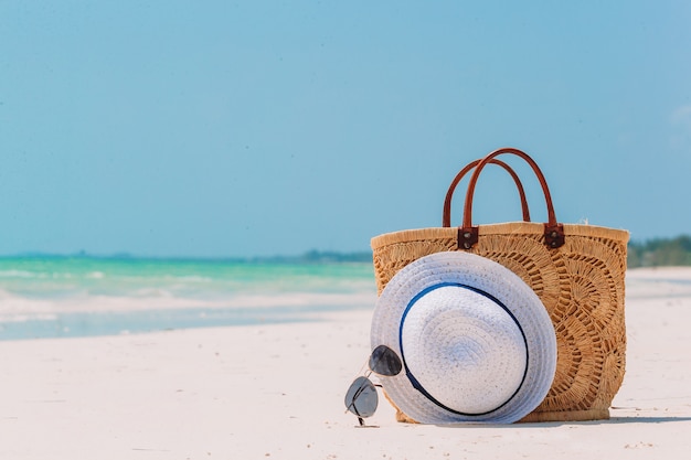 Accessoires de plage - sac de paille, chapeau et lunettes sur la plage