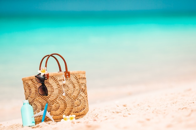 Accessoires de plage - sac de paille, chapeau et lunettes sur la plage