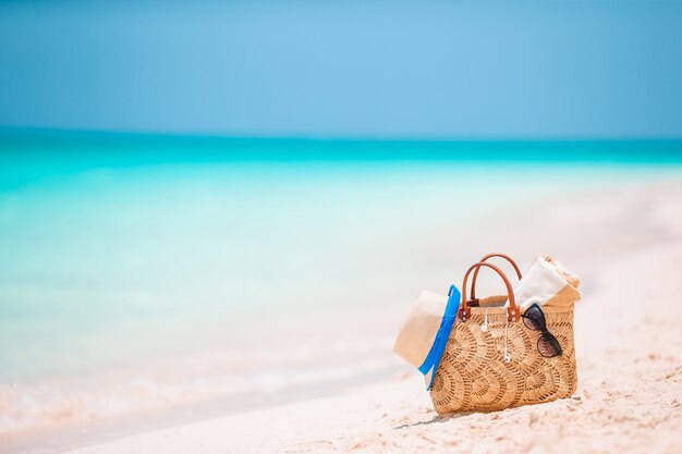 Accessoires de plage - sac de paille, chapeau et lunettes sur la plage