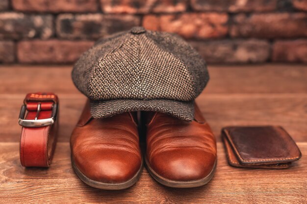 Photo accessoires pour hommes chaussures en cuir marron portefeuille casquette en laine et ceinture en cuir sur fond de bois