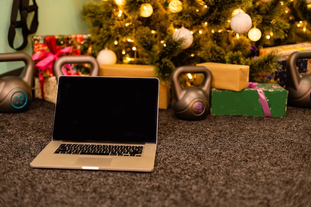 Accessoires sportifs. Haltères, tablette informatique, branches de sapin et décorations de Noël sur fond. Vue de dessus avec espace de copie. Remise en forme, sport et mode de vie sain.