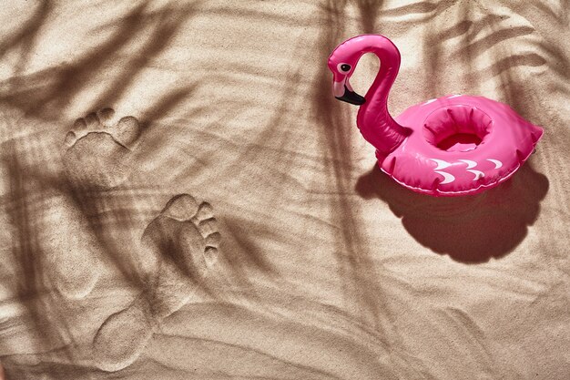 Les accessoires de vacances des voyageurs sont disposés sur une plage de sable blanc vue de dessus à plat