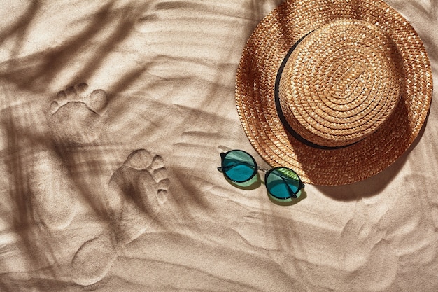 Les accessoires de vacances des voyageurs sont disposés sur une plage de sable blanc vue de dessus à plat