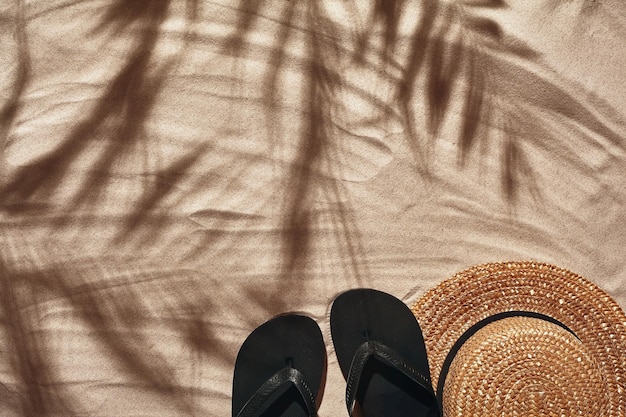 Les accessoires de vacances des voyageurs sont disposés sur une vue de dessus de plat de sable de plage blanche