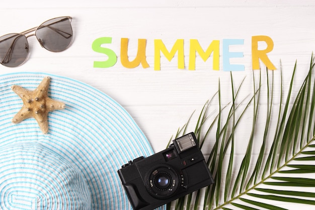Accessoires de voyage et feuilles tropicales sur un fond coloré vue de haut
